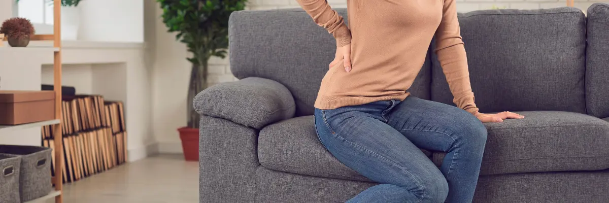ソファーに座ると腰が痛い女性のイメージ（名古屋市千種区テソラ治療院