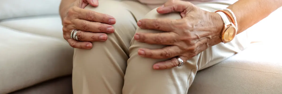 両手で膝を抱えて痛みに耐える高齢女性の様子